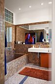 Mosaic-tiled, brown designer bathroom with masonry bathtub and minimalist washstand