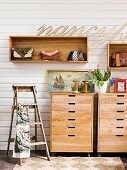 Vintage-style hall decor - lettering above handbags in wall-mounted shelving units; old, painter's stepladder and still-life arrangement on wooden chests of drawers