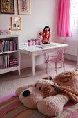 Pink Philippe Starck ghost chair at a desk in a girls bedroom