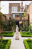 Symmetrically designed courtyard with a statue, boxwood hedge and paved walkway