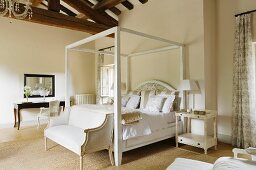 White four poster bed below high beamed ceiling of Provence country house