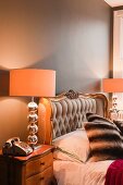Prunkvolles Bett mit gestepptem Kopfende und vergoldetem Rahmen; auf jeder Seite eine Nachttischlampe mit silberglänzendem Lampenfuss