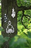 White, ornate candle sconces hung on tree in garden