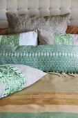 Embellished linen scatter cushions against quilted headboard of bed with striped linen bedspread
