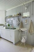 Corner of white, Scandinavian kitchen with pitcher and basin on nostalgic, delicate washstand below wall-mounted mirror