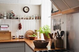 Open shelving and solid oak work surfaces in kitchen with white wooden wall panels