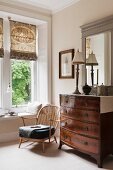 Antique George III style wooden chest of drawers adjacent to a low windsor chair with cushion