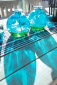 Blaue Glasbehälter mit Docht und Brennflüssigkeit auf Tisch mit Tischläufer im Freien
