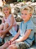 Junge und Mädchen sitzen auf einer Holztreppe im Freien