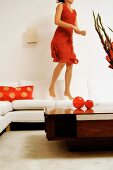 Frau im roten Kleid hüpft auf einem Sofa