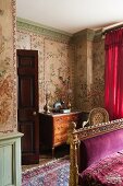 Chinese wall panels of painted rice paper, gilt bed frame and velvet throw embroidered with gold thread in stylish bedroom