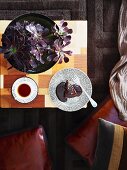 Top view of potted plant and tea cup and side plate in Oriental style (chinoiserie) on patchwork wooden table