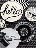 Various plates with black and white patterns and lettering on tablecloth with three-dimensional pattern