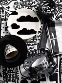 China plates and cups painted with black and white motifs on black and white patterned tablecloth