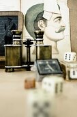 Vintage binoculars and dice on table in front of old drawing