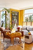 Corner of yellow-painted living room with lounge area and shiny gold sheep sculpture on zebra-skin rug