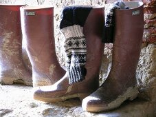 Muddy wellington boots and knitted socks on old stone terrace