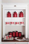 Red, retro style canisters in an white, open storage cabinet