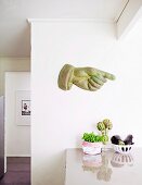 Hand sculpture with an extended index finger on a white wall above the kitchen counter