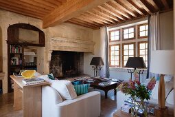 New wooden ceiling within old walls - interior with white sofas in front of large inglenook fireplace