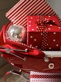 Weihnachtsgeschenke und Dekokugel in einem roten Kinderwagen
