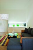 Schlichtes Sofa übereck und Klassiker Couchtisch auf Streifenteppich in minimalistischem Wohnzimmer