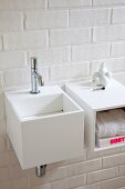 Cubic sink and shelf mounted on white brick wall
