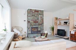 Wohnraum mit einfachen, hellen Möbeln und natursteinverkleidetem Kamin