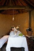 Festively set dining table in small, rustic room with exposed brick roof structure