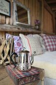 Silberne Teekanne und Buch auf einem rustikalen Nachttisch neben dem Bett