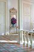 Balustrade, painted wooden column and tall doors with gilt ornamentation in foyer of stately home