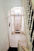 Gedrechseltes Geländer im Treppenabgang eines klassischen Hausflurs und Blick auf verglasten Windfang