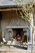 Veranda with columns, fire in large open fireplace and vintage table and chairs