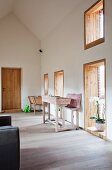 Foyer with bureau and bench against wall between window and door with wood-clad reveals