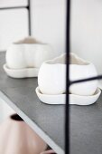 Two china pots on grey shelf with metal frame