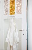 White guest kimono hanging on bathroom door with mirrored insert and embossed ornamental panels