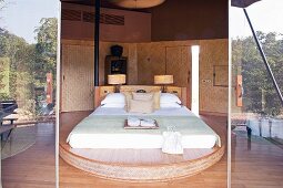 View through open door into elegant bedroom with double bed on curved platform