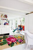 Familie im weissen, offenen Wohnraum mit grossformatigem Rosenmuster-Kelim