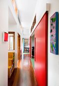 Corridor with red sliding doors and various transom window elements leading between open-plan rooms