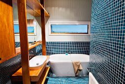 Blue mosaic tiles and washstand with exotic wood fixtures in bathroom