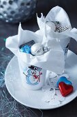 Snowman beakers filled with Christmas tree baubles and chocolate hearts