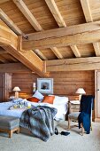 Breakfast tray on double bed below massive wooden ceiling beams in rustic bedroom