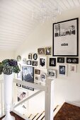 Gallery of photographs on wall of staircase with white-painted wooden elements and mosaic parquet floor