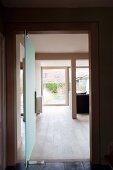 Offene Zimmertür aus satiniertem Glas; Blick über den Dielenboden im Wohnraum bis in den Garten