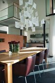 Leather-covered designer chairs at dining table and designer pendant lamps