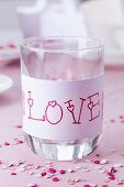 Drinking glass used as lantern and decorated with 'Love' written on paper