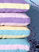 Stack of cushions with striped covers in different pastel shades
