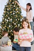 Girl holding Christmas gift in front of family
