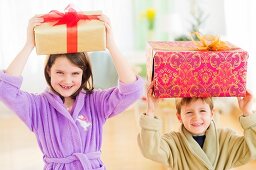 Mädchen und Junge tragen Weihnachtsgeschenke auf ihren Köpfen