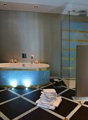Elegant bathroom with pastel blue and gold mosaic tiles on bathtub and walls; tiled floor with diamond pattern